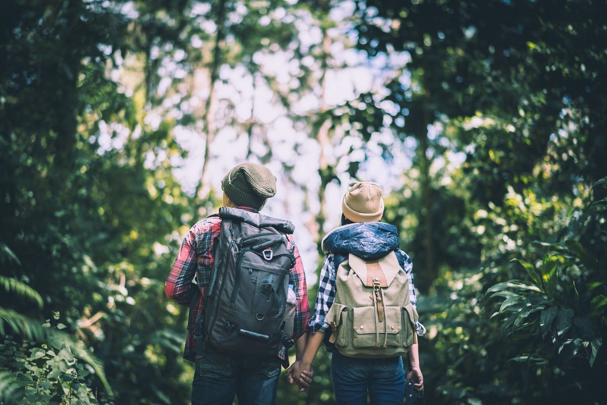 Young couple walking with backpacks in forest. Adventure hikes, Enjoy holidays together,